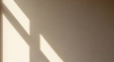 Güneş ışığı düz bir duvar boyunca cesur çapraz gölgeler oluşturur, sakin, minimal mimari ışık desenlerini yakalar..