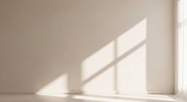 A minimalist interior scene showing warm sunlight streaming through a window and creating sharp rectangular shadows across a plain wall.