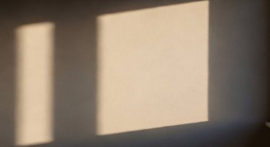 Sıcak ışık ve gölgeli pencere camları geometrik dikdörtgenler ve yumuşak tonlarla sakin bir iç mekan oluşturur..