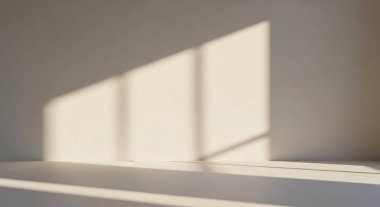 Soft daylight forms geometric shadows on a bare interior wall, creating a calm minimalist atmosphere.