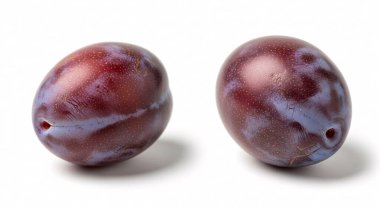 İki olgun erik, parlak mor derileri ve doğal ışık yansımalarını gösteren beyaz bir zeminde dinlenir..