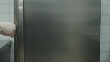 Eldiven giyen biri buzdolabını açar, içine taze sebze konteynırı koyar ve kapıyı kapatır. Mutfak ayarları.