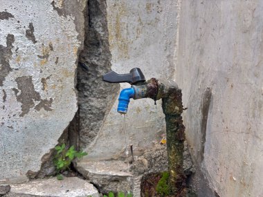 Eski, paslı bir musluğun yakın plan görüntüsü. Su damlıyor, zamanın ve ihmalkarlığın etkilerini vurguluyor. Çürümeyi, çevresel kaygıları ya da kentsel konuları resmetmek için mükemmel. Yaş ve unutulmuş yerleri çağrıştırıyor..