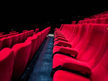 Karanlık bir sinemada kırmızı koltukları olan bir sinema salonu.