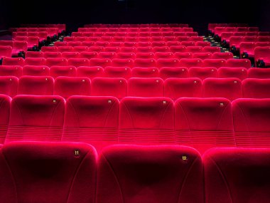 Karanlık bir sinemada kırmızı koltukları olan bir sinema salonu.