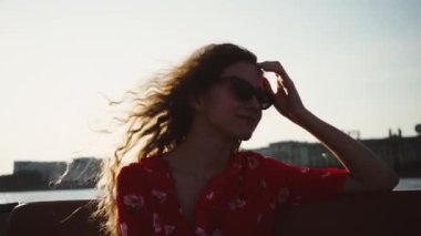 Kafkasyalı genç turist kız ya da kadın teknede oturuyor ve Saint-Petersburg şehrine bakıyor. Rusya, Ağır çekim.