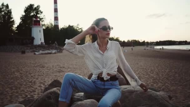ラドーガ湖のほとりのビーチでリラックスしている若い白人の女の子。オイノヴェツキー灯台 — ストック動画