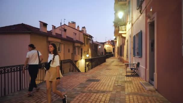 Το κορίτσι με τις μπούκλες εξερευνά την παλιά πόλη της Γαλλίας. Ευτυχισμένη νεαρή γυναίκα με λευκό μπλουζάκι στην αρχαία πόλη των Καννών. Χιλιετηρίδα βόλτες στην πόλη. Μοντέρνο βλέμμα σε vintage ρετρό στυλ. — Αρχείο Βίντεο