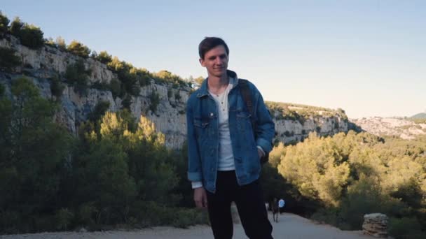 Ten chlap má rád přírodu, hory a azurové moře. Mladý muž prozkoumává skály na jihu Francie. Módní postava v džínách a retro stylu. Tropická krajina v Cassis. — Stock video