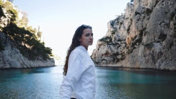 La ragazza ama la natura, le montagne e il mare azzurro. Una giovane donna esplora le rocce nel sud della Francia. Personaggio alla moda in jeans in stile vintage. Paesaggio tropicale a Cassis. — Video Stock