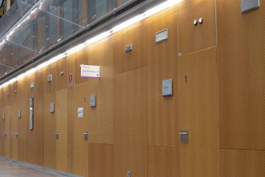 Hastane koridoru ahşap paneller ve tabelalarla modern sağlık hizmetleri çevresi ve hasta deneyimini temsil ediyor.