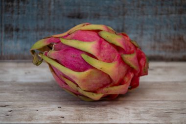 Ejderha meyvesi, taze, sağlıklı ve egzotik bir süper yiyecek, kırsal arka planı olan açık tahta bir masada dinleniyor.