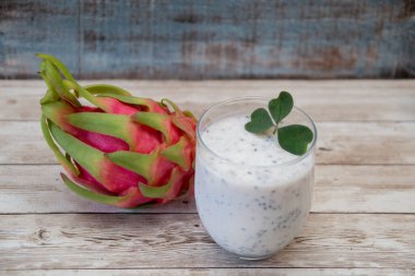 Ejderha meyvesi ve bir bardak taze pitaya chia tohumu smoothie ile ahşap bir yüzey üzerinde yonca yaprağı