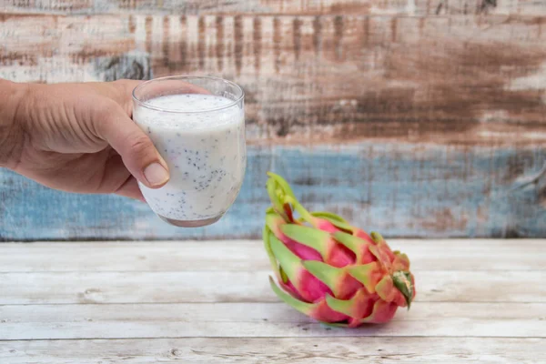 El ele tutuşarak taze pitaya smoothie ile chia tohumları, sağlıklı ve taze bir kahvaltı içeceği sunarak, tüm ejderha meyvelerinin yanında