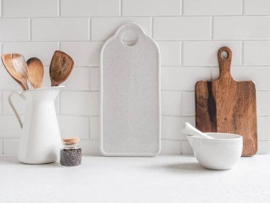 Beyaz mutfak arka planında mutfak aletleri ve beyaz tezgahtaki yazı için beyaz seramik tahta, kopyalama alanı, ön görünüm