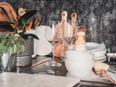 Tabaklar, şarap bardakları, mutfaktaki lavaboda sabunlu köpükler. Ön görünüm