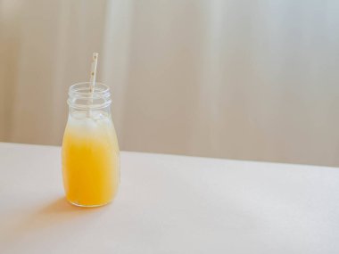 Cam şişe buzlu sarı meyve suyu ve tahta masanın üzerinde kağıt kamış. Yaz meyvesi asgari konsept. Ön görünüm.