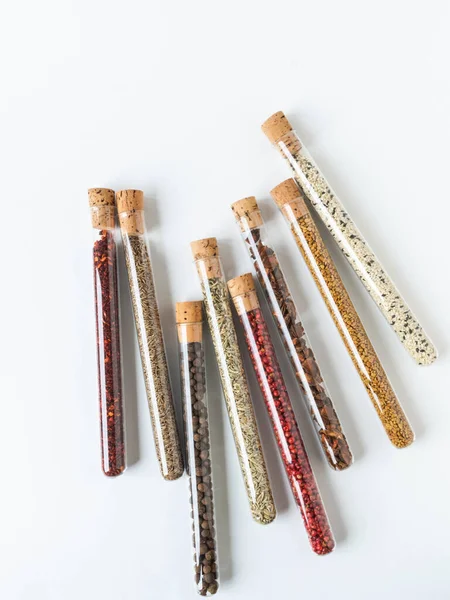 Beyaz arka planda tıpası olan cam tüplerdeki çeşitli kuru baharatlar. Uzayı kopyala Üst görünüm