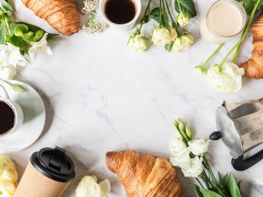 Düz kahve çerçevesi, çiçekler ve kruvasan mermer zemin üzerinde yatıyordu. Fransız kahvaltı konsepti. Üst Manzara. Boşluğu kopyala