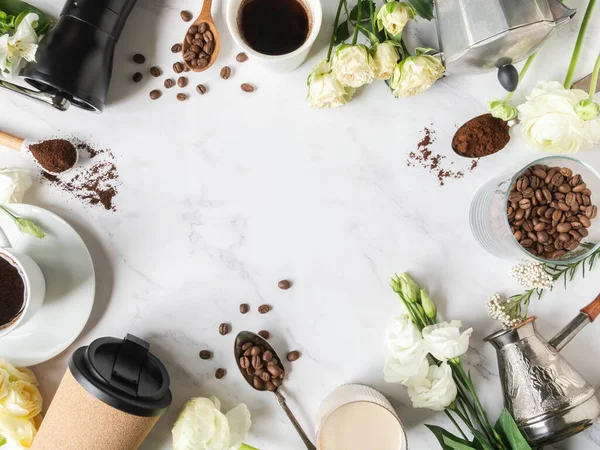 Flat lay frame of coffee, flowers, various utensils for making coffee and cups of coffee on white marble background. Coffee concept. Top view. Copy space