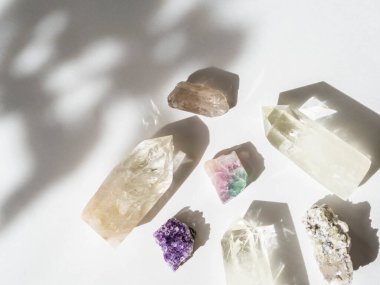 Güneş ışığının gölgeleriyle beyaz arkaplandaki mineral kristallerinin toplanması