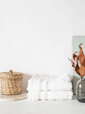 Beyaz banyo arkaplan manzarası, cam vazo, beyaz havlular ve beyaz raf ve duvarda dekor. Ön manzara. Boşluğu kopyala