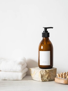 Beyaz kehribar kehribar cam şişe grange doğal taş, ahşap masaj aleti ve beyaz arka planda beyaz havlular. Ön görünüm