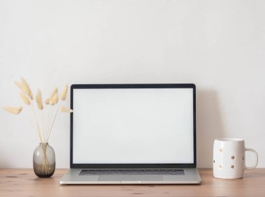 Ev ofis masası, dizüstü bilgisayarı açık vazoda kuru sonbahar dalları ve beyaz bardak manzaralı. Boşluğu kopyala