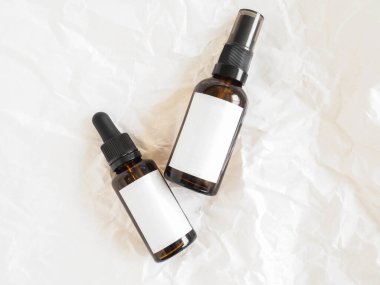 Bakım kozmetik ürünleri için bir model - iki kehribar şişesi üzerinde beyaz etiketler olan buruşuk beyaz kağıt arka plan. Üst Manzara. Boşluğu kopyala