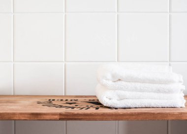Banyo arkaplan manzarası, kahverengi ahşap raflarda beyaz havlular ve duvar fayansları. Ön manzara. Boşluğu kopyala