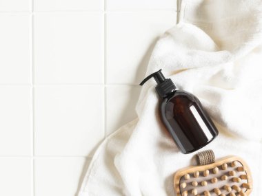 Banyodaki banyo ürünleri için kahverengi şişe maketi, spa şampuanı, duş jeli, pamuk havluda sıvı sabun ve tahta masaj aleti düzlüğü. Üst Manzara. Boşluğu kopyala