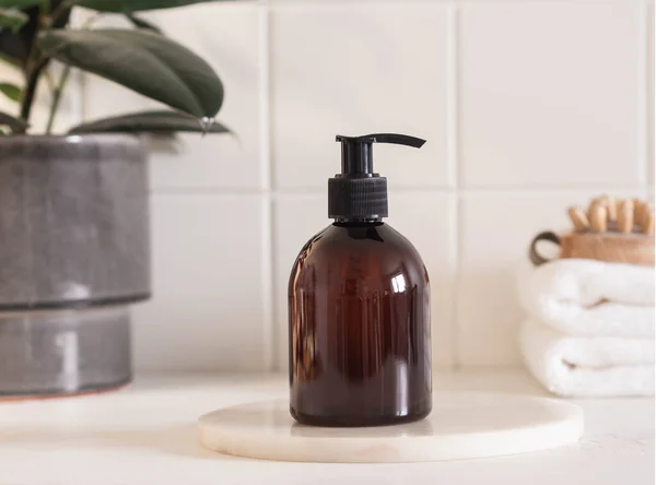 Banyodaki banyo ürünleri için kahverengi şişe modeli, spa şampuanı, duş jeli, mermer kürsüde sıvı sabun ve çeşitli aksesuarlar..