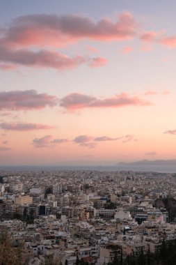Güneş batarken Atina 'nın panoramik manzarası. Pembe bulutlar ve Ege Denizi üzerinde sıcak pastel gökyüzü. Seyahat ve şehir manzarası geçmişi.