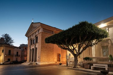 Scilla, İtalya - 26 Eylül 2025: Aydınlık cepheli ve sakin bir kent meydanında alacakaranlıkta ağaç şekilli tarihi kilise.