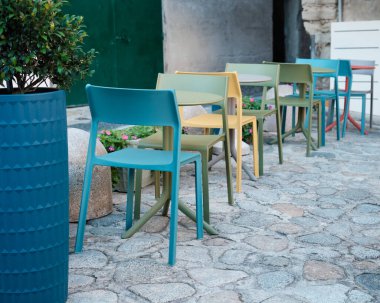 Renkli açık hava kafe sandalyeleri ve masalar kaldırım taşından bir avluda, konukseverlik, açık hava yemekleri ve şehir yaşam tarzı kavramları için ideal.