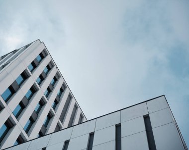 Fotokopi alanı ile bulutlu gökyüzüne karşı çağdaş bir ofis binasının modern düşük açılı görüntüsü, şirket, iş ve teknoloji arka planı için ideal.