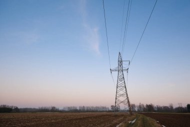 Yüksek voltaj iletim kulesi ve kırsal arazi üzerindeki elektrik hatları fotokopi alanı ile temiz bir gökyüzü altında, kullanım alanı, şebeke ve elektrik tedarik kavramları için temiz bir enerji altyapısı oluşturur..