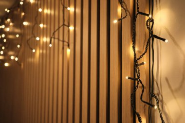 Ahşap bir duvar üzerinde bokeh ile sıcak sicim ışıkları, metin için kopya alanı ile iç arkaplan.