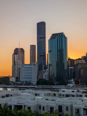 BRISBANE, QUEENSLAND, AUSTRALIA, 6 ARALIK 2025, Brisbane şehri, Brisbane Nehri boyunca modern yüksek ofis kuleleri ile gökyüzü altında yerleşim çatıları.