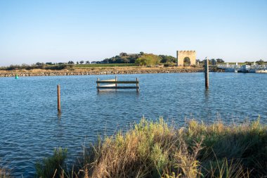 Önünde bir kapı olan büyük bir kemer yolu. Kemer yolu taştan yapılmış ve kapı metalden yapılmış. Gökyüzü açık ve mavi. Villeneuve-les-Maguelone 'da, Fransa' nın güneyinde Herault Bölümü 'nde bir kasaba.