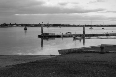 Limanda bir kaç teknenin olduğu siyah beyaz bir fotoğraf. Su sakin ve gökyüzü bulutlu. Gavres Yarımadası, Britanya, Fransa