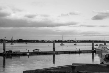 Limanda bir kaç teknenin olduğu siyah beyaz bir fotoğraf. Su sakin ve gökyüzü bulutlu. Gavres Yarımadası, Britanya, Fransa