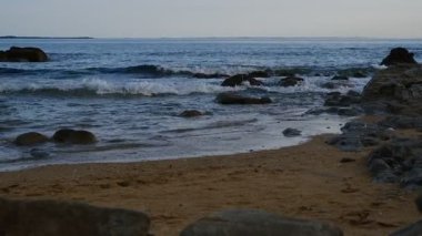 4K sabit çekim videosu Erdeven, Brittany 'deki kayalık bir plaja düşen karamsar ve çalkantılı deniz dalgalarını gösteriyor. Fırtınalı havaya ve dramatik kıyı manzarasına odaklan.