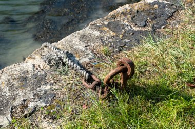 Paslı bir zincir bir duvarın yanındaki çimlerin üzerinde yatıyor. Zincir bir kayaya bağlı ve çimenler yeşil ve yemyeşil. Zincir terk edilmiş gibi görünürken, sahne biraz melankolik bir ruh haline sahip.