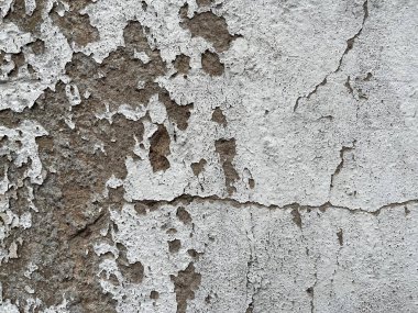 Çatlamış beton bir duvara yakın plan beyaz boya ve pürüzlü, yıpranmış bir doku. Geçmişler, yaşlanma, çürüme veya kentsel tasarım temaları için idealdir.