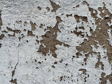 Close-up of peeling paint on a weathered wall, revealing a rough brown surface beneath. Ideal for textured backgrounds or vintage, rustic design elements.