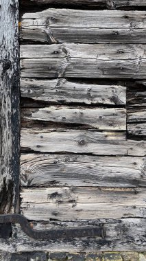 Yıpranmış ahşap levhalar yatay olarak dizilmiş, derin çatlakları, pürüzlü tahılları ve eskimiş kenarları olan gri renkleri ve kırsal bir doku için paslı metal donanımı gösteriyor..