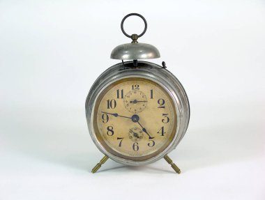 Yuvarlak yüzlü klasik metal çalar saat, eski bej tuşlar, siyah rakamlar, ve pirinç bacaklar, beyaz arka planda klasik bir çan var..