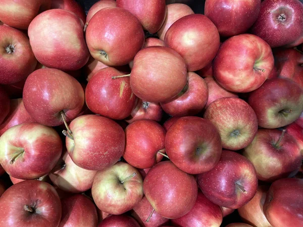 Pürüzsüz cilt ve doğal renk değişimlerine sahip taze kırmızı elma yığını canlı ve sağlıklı bir meyve arkaplanı oluşturur..