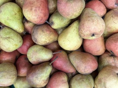 Yeşil ve kırmızımsı renklere sahip taze armut yığınının yakın çekimi, gıda, sağlık ve organik üretim kavramları için ideal doğal bir meyve arka planı oluşturur..